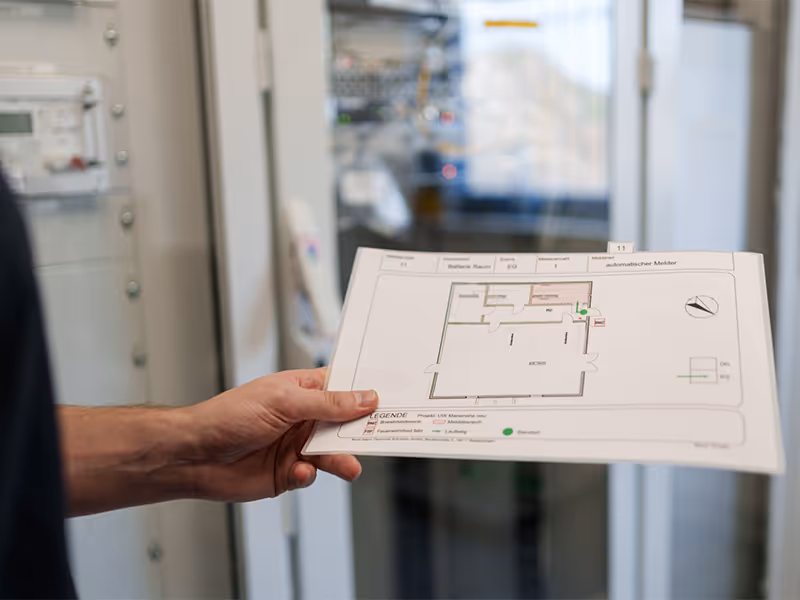 Informationselektroniker mit einem Installationsplan für Sicherheitstechnik.