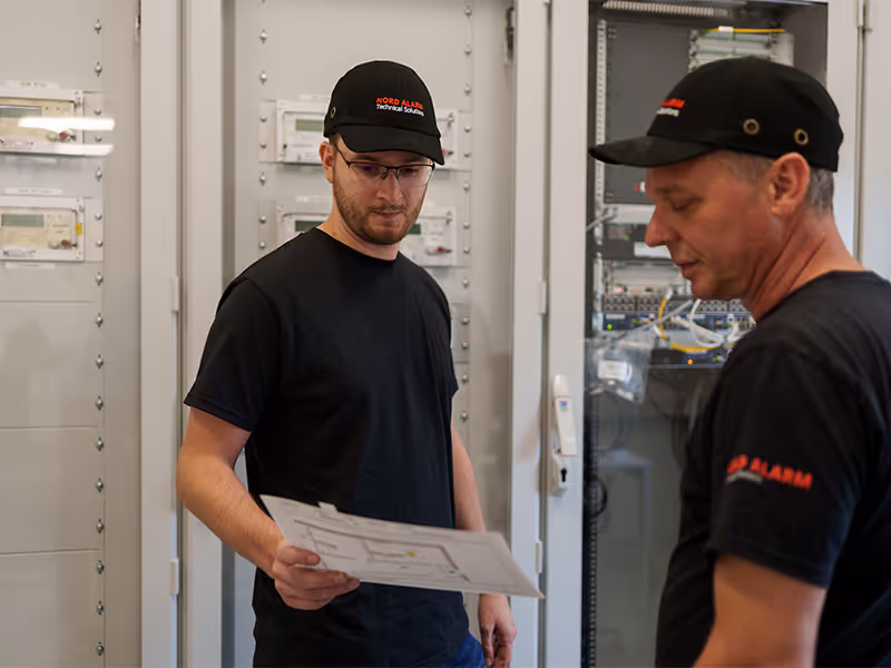 Zwei Fachleute für Sicherheitstechnik installieren und verkabeln Alarmanlagen und Sicherheitstechnik an einem Bürogebäude in Rostock.